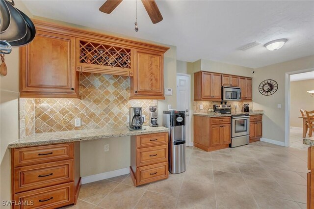 kitchen featuring light stone counters, backsplash, stainless steel appliances, and light tile patterned flooring