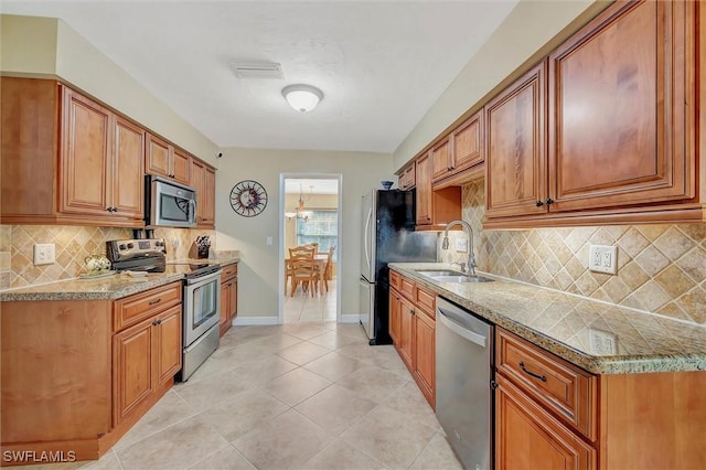 715 96th Ave N, Naples, FL 34108 - kitchen featuring appliances with stainless steel finishes, a sink, brown cabinets, and light tile patterned flooring