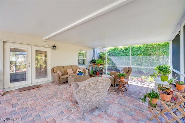 sunroom / solarium featuring beam ceiling and french doors