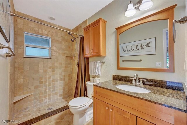 bathroom featuring tile patterned flooring, vanity, a shower with shower curtain, and toilet