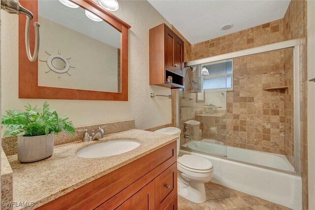 full bathroom with vanity, toilet, and combined bath / shower with glass door