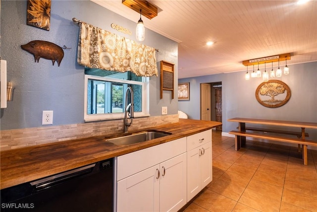 kitchen featuring sink, black dishwasher, white cabinets, wood counters, and decorative light fixtures