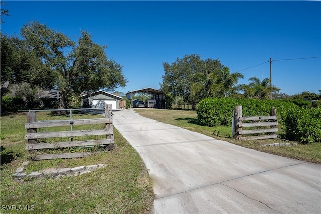 view of gate with an outbuilding, a garage, a lawn, and a carport