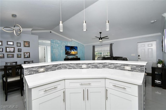 kitchen with white cabinetry, backsplash, hanging light fixtures, ornamental molding, and vaulted ceiling