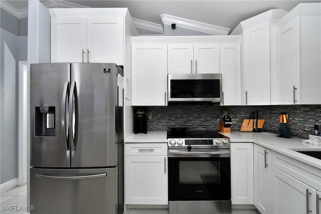 kitchen featuring light tile patterned flooring, white cabinetry, backsplash, ornamental molding, and stainless steel appliances