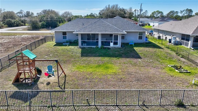 rear view of house featuring a yard, a sunroom, and a playground