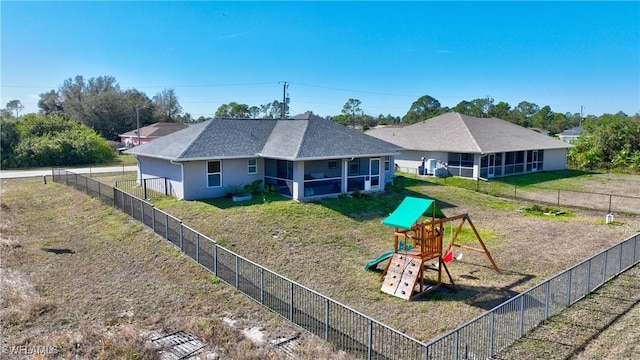 rear view of house with a lawn, a sunroom, and a playground