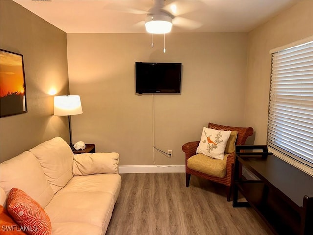 living area featuring wood finished floors, a ceiling fan, and baseboards