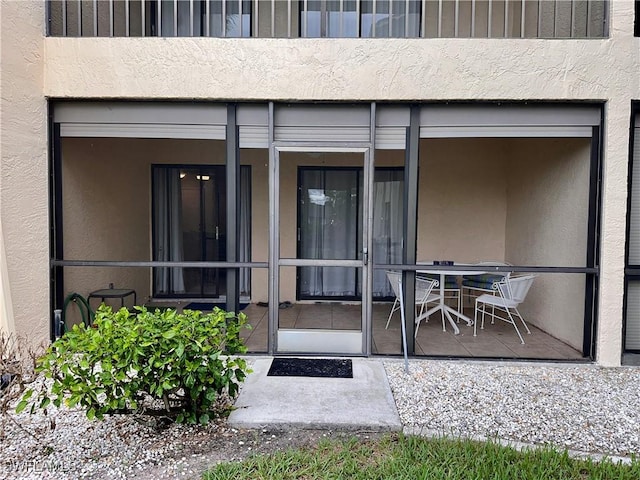 entrance to property featuring a balcony, a patio area, and stucco siding