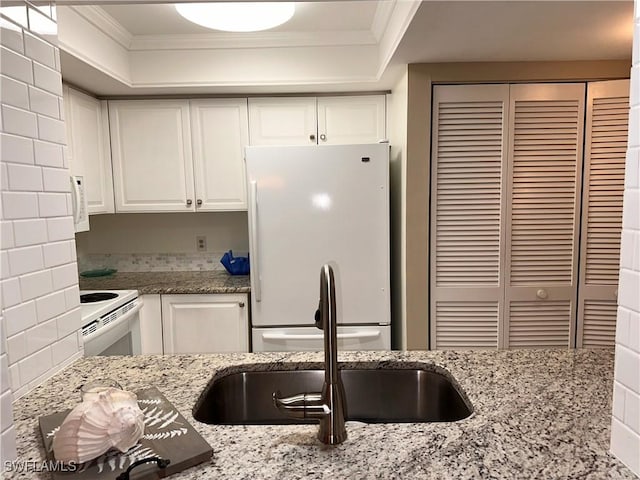 kitchen featuring white appliances, light stone counters, white cabinets, and crown molding