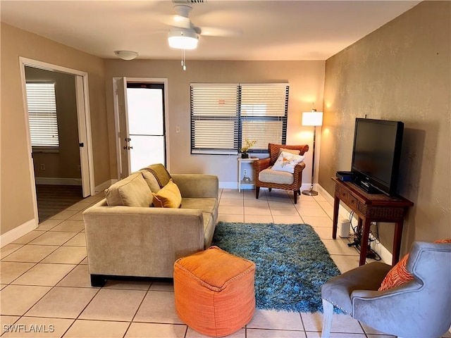 living room with light tile patterned floors, ceiling fan, and baseboards