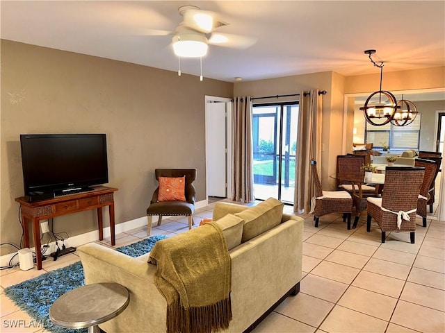 living area with light tile patterned floors, ceiling fan with notable chandelier, and baseboards