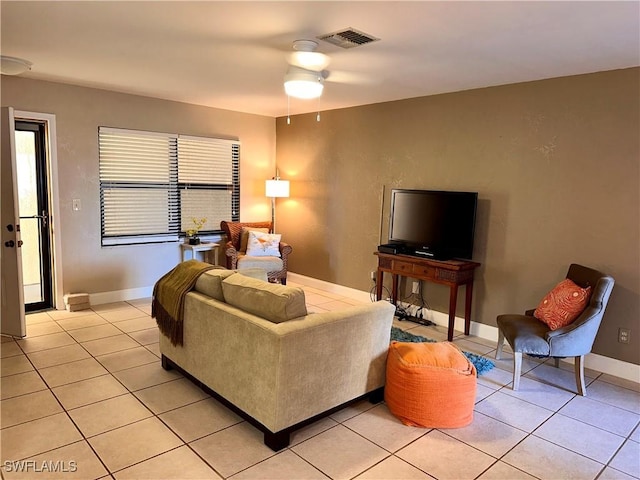 living area with light tile patterned floors, baseboards, visible vents, and ceiling fan