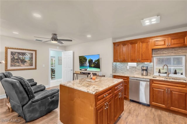 kitchen with sink, ceiling fan, light stone counters, a kitchen island, and stainless steel dishwasher