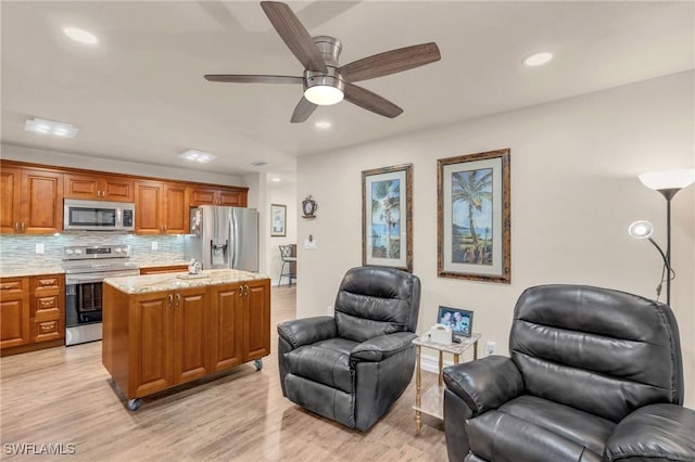 kitchen featuring light hardwood / wood-style flooring, ceiling fan, stainless steel appliances, a center island, and decorative backsplash