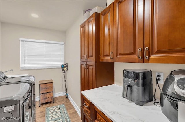 washroom featuring washer and dryer, light hardwood / wood-style flooring, and cabinets