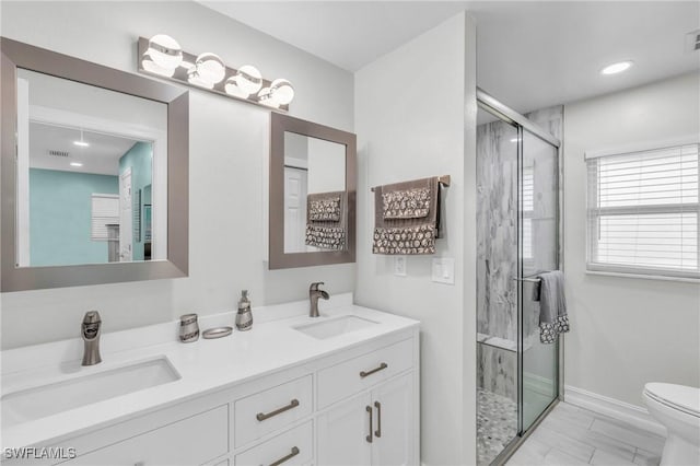 bathroom featuring vanity, a shower with shower door, and toilet