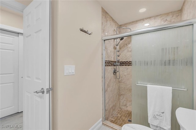 bathroom featuring toilet and a shower with shower door