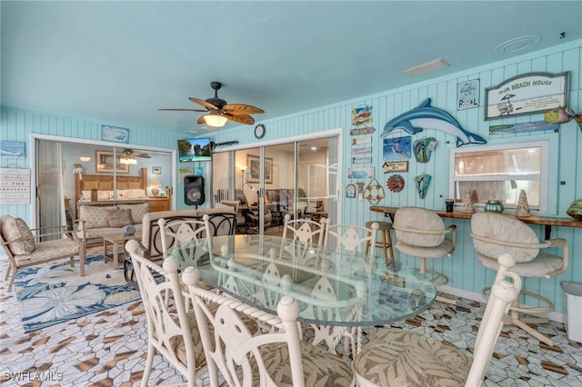 dining room featuring ceiling fan and wooden walls