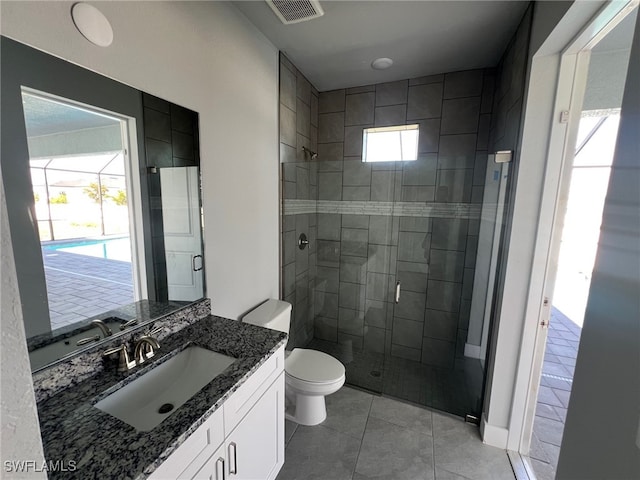 bathroom with a shower with door, vanity, tile patterned floors, and toilet