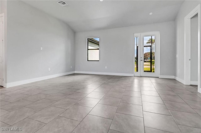 empty room with visible vents, vaulted ceiling, baseboards, and light tile patterned flooring