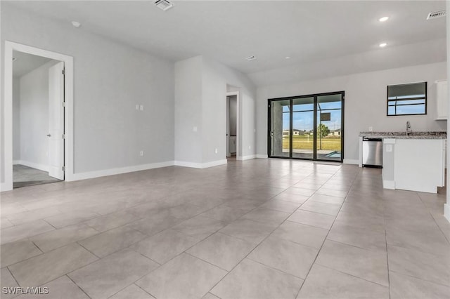 unfurnished living room featuring recessed lighting, visible vents, light tile patterned flooring, a sink, and baseboards