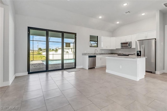 kitchen with visible vents, white cabinets, a kitchen island, appliances with stainless steel finishes, and vaulted ceiling