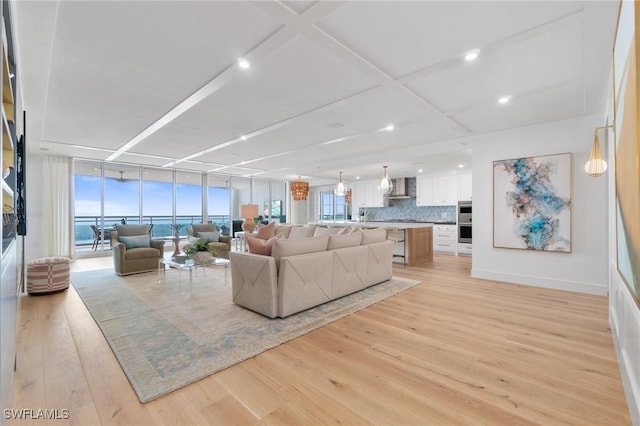 living room featuring a water view, coffered ceiling, and light hardwood / wood-style flooring