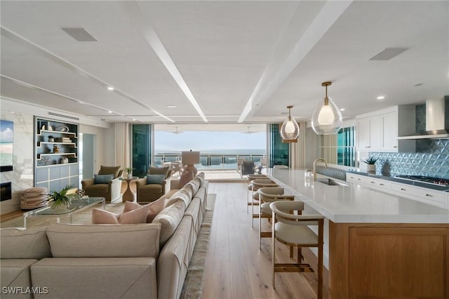 living room with floor to ceiling windows, sink, and light wood-type flooring