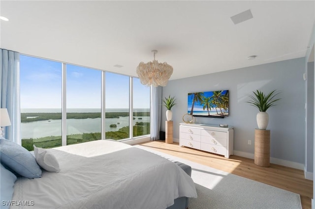 bedroom with hardwood / wood-style floors, a notable chandelier, and floor to ceiling windows