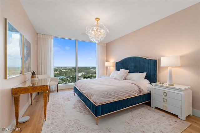 bedroom with a notable chandelier, floor to ceiling windows, and light wood-type flooring