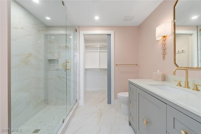 bathroom featuring a shower with door, vanity, and toilet