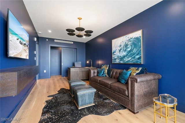 cinema room featuring an inviting chandelier and light wood-type flooring