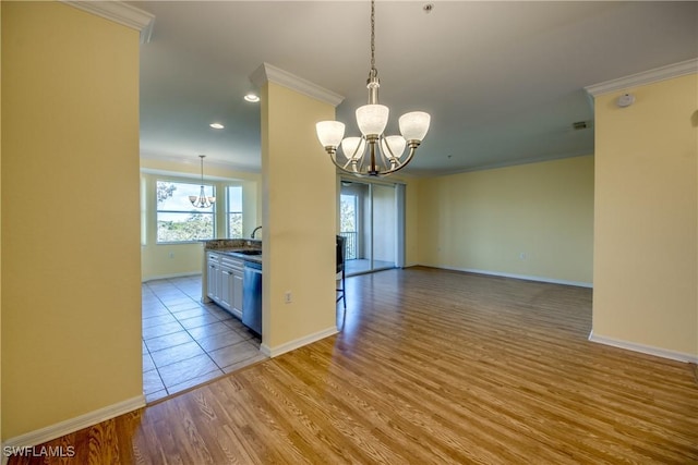 kitchen featuring dishwasher, ornamental molding, sink, and an inviting chandelier