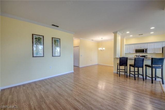 living room featuring an inviting chandelier, crown molding, and light wood-type flooring