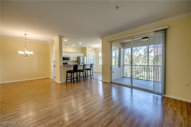 living room featuring hardwood / wood-style flooring, crown molding, and ceiling fan with notable chandelier