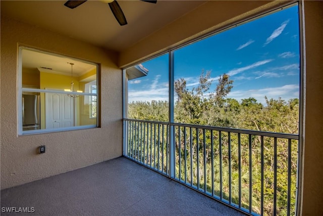 unfurnished sunroom featuring ceiling fan with notable chandelier