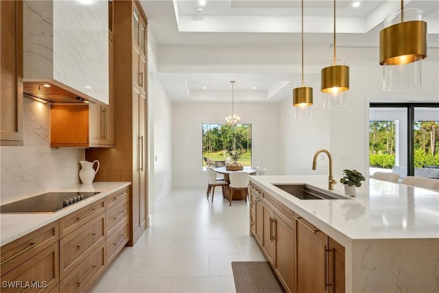 kitchen with a spacious island, wall chimney exhaust hood, sink, decorative light fixtures, and a tray ceiling