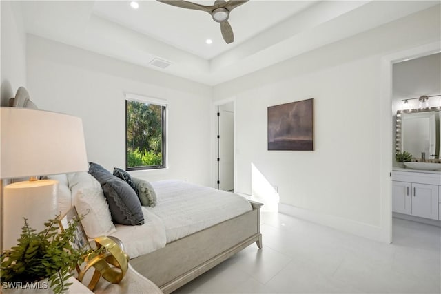 bedroom with ceiling fan, ensuite bathroom, a raised ceiling, and sink