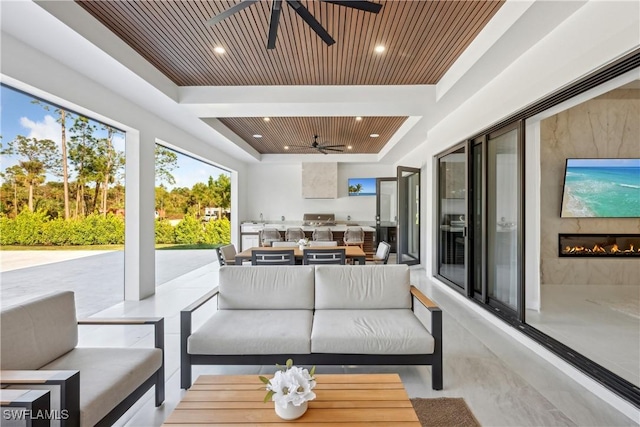 sunroom / solarium featuring wooden ceiling, ceiling fan, and a tray ceiling