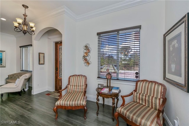 sitting room with an inviting chandelier, crown molding, and dark wood-type flooring