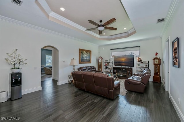 living room with ceiling fan, ornamental molding, dark hardwood / wood-style floors, and a raised ceiling