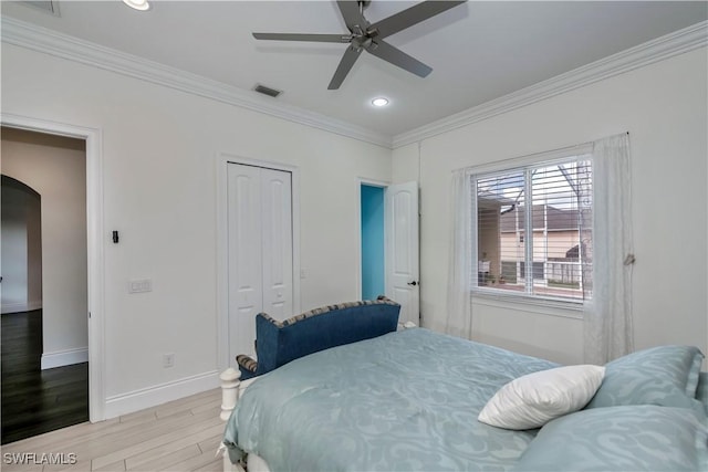 bedroom with a closet, ornamental molding, light hardwood / wood-style floors, and ceiling fan