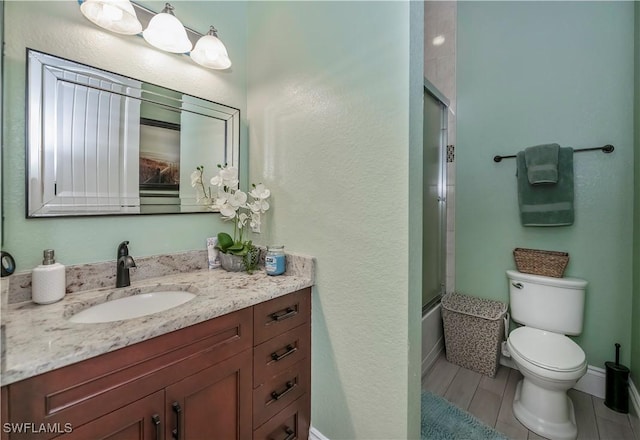 full bathroom with toilet, vanity, and bath / shower combo with glass door