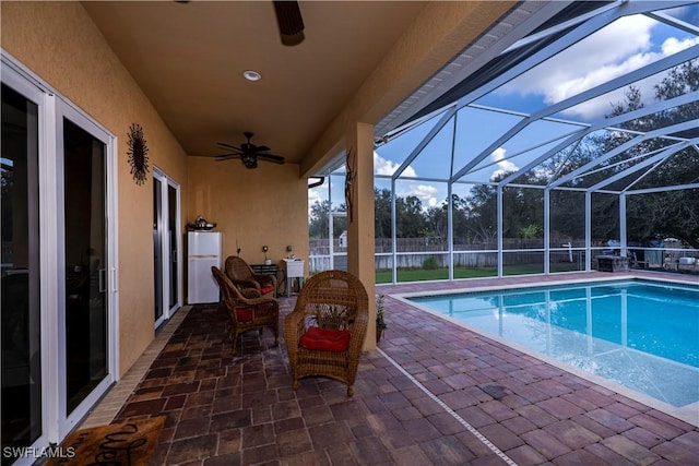 view of swimming pool featuring ceiling fan, a patio, and glass enclosure