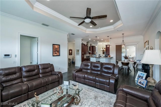 living room with wood-type flooring, ornamental molding, ceiling fan, and a tray ceiling