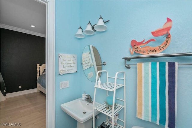 bathroom with hardwood / wood-style flooring, crown molding, and sink