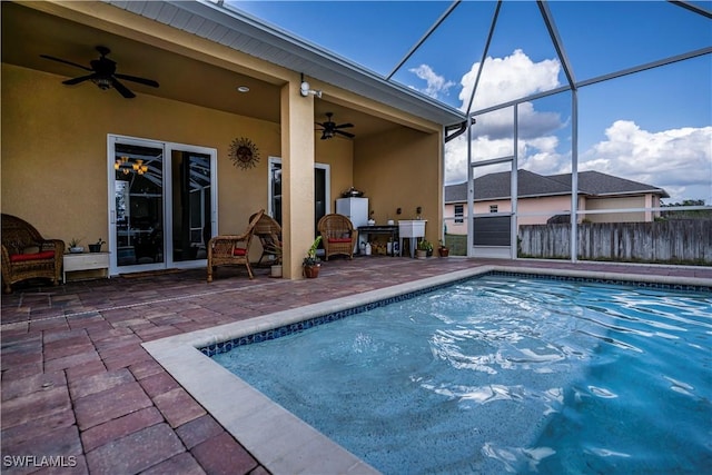 view of swimming pool with a patio area, ceiling fan, and glass enclosure