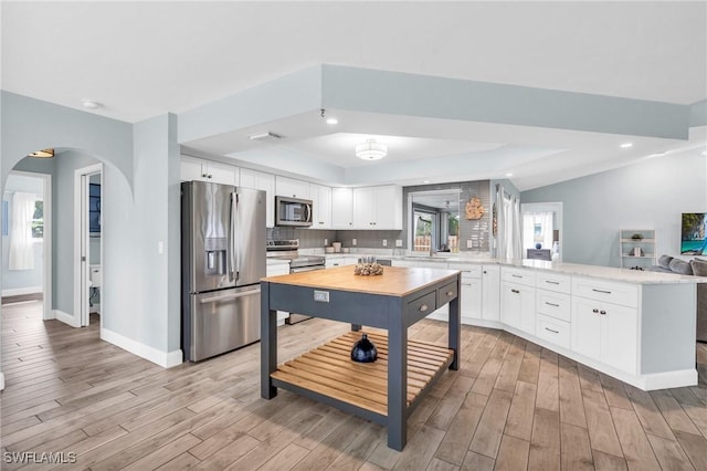 kitchen with white cabinetry, appliances with stainless steel finishes, light hardwood / wood-style floors, and tasteful backsplash