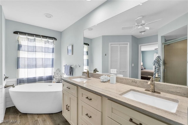 bathroom with hardwood / wood-style flooring, ceiling fan, vanity, and a bath